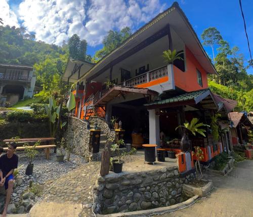 a man sitting in front of a building at Garden Grove Guest House & Coffee Bar in Bukit Lawang