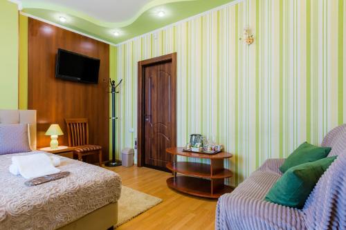 a bedroom with a bed and a chair and a television at Poznyakoff Aparthotel in Kyiv