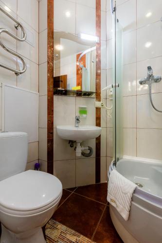a bathroom with a toilet and a sink and a tub at Poznyakoff Aparthotel in Kyiv