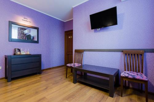 a room with a table and chairs and a tv on a purple wall at Poznyakoff Aparthotel in Kyiv