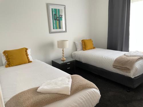 a bedroom with two beds and a lamp on a table at Winterwood Lodge - 6mins Jindabyne Pets Allow Farm Stay-Swimming Pool Summer Only in Moonbah