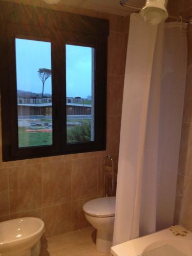 a bathroom with a toilet and a window at Hostal Santa Baia in Ribadumia