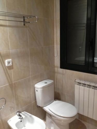 a bathroom with a white toilet and a sink at Hostal Santa Baia in Ribadumia