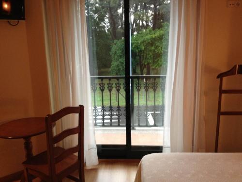 a bedroom with a window with a view of a balcony at Hostal Santa Baia in Ribadumia