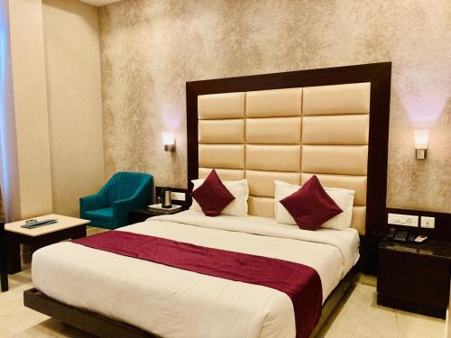 a bedroom with a large bed and a green chair at Hotel The Onix in Dehradun