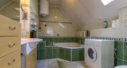 a bathroom with a tub and a sink and a washing machine at Eva Rooms in Budakeszi