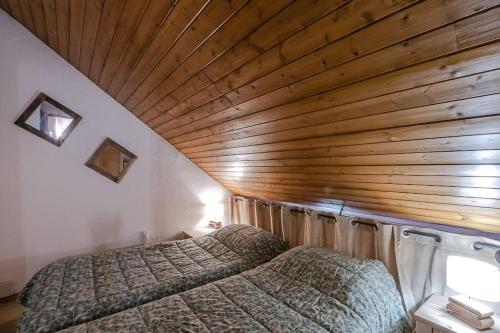 two beds in a room with a wooden ceiling at Bel appartement entier en style Chalet à Chamonix in Chamonix