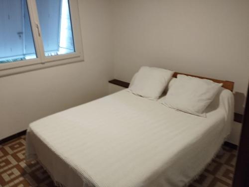 a white bed with two pillows in a room with a window at Le Porche in Saint-Paul-des-Fonts