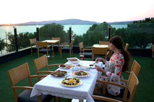 a woman sitting at a table with plates of food at Çamlık 87 Hotel Ayvalık in Ayvalık