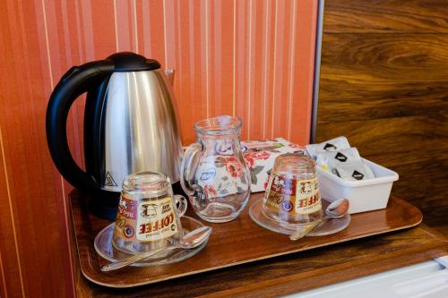 a tea kettle and glasses on a wooden tray at Poznyakoff Aparthotel in Kyiv