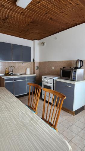 uma cozinha com uma mesa, 2 cadeiras e um lavatório em Kuća djeda Ive 