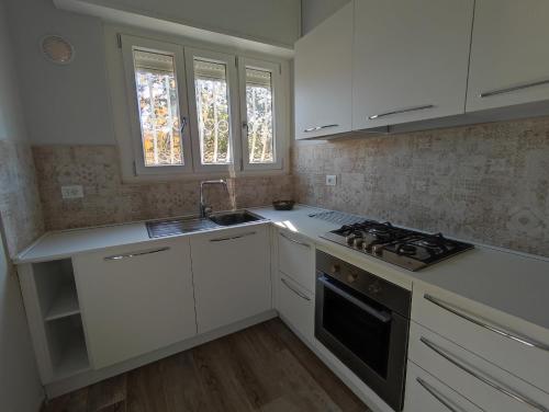 una cucina con armadi bianchi, lavandino e piano cottura di Casa Violina a Lido di Camaiore