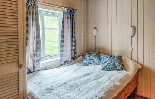 a bedroom with a bed with two pillows and a window at Stunning Home In Mosvik With House Sea View in Mosvik