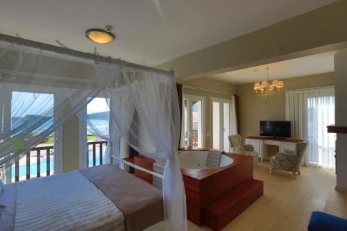 a bedroom with a bed and a tub and a television at Datca Doris Hotel in Datca