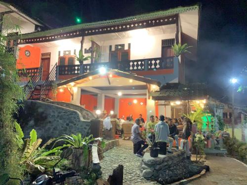 a group of people standing outside of a building at night at Garden Grove Guest House & Coffee Bar in Bukit Lawang