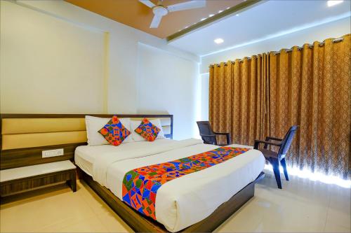 a bedroom with a bed and two chairs and a window at FabHotel Ramjis Residency in Nashik