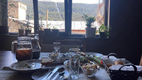 a table with plates of food on it with a window at Guesthouse Chela in Mestia