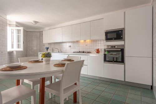 a white kitchen with a table and white cabinets at Appartamenti Frontemare in Marina di Mancaversa