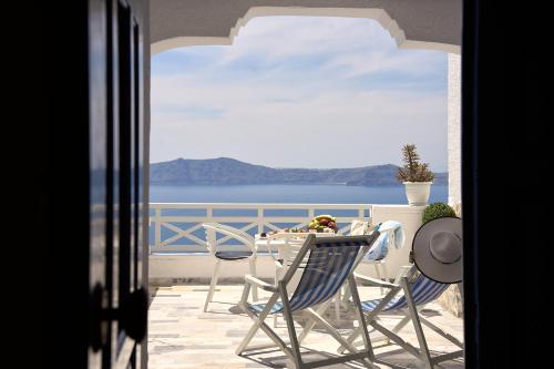 d'une table et de chaises sur un balcon avec vue sur l'océan. dans l'établissement Amphitheater Cave Houses, à Fira