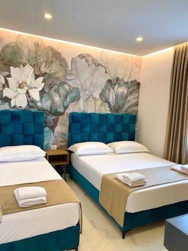 two beds in a room with a mural on the wall at Apartments Oda Hotel in Velipojë