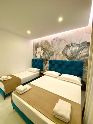 two beds in a room with a painting on the wall at Apartments Oda Hotel in Velipojë