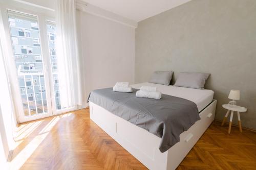 a white bedroom with a large bed and a large window at Cozy 2 bedroom apartment close to center in Split