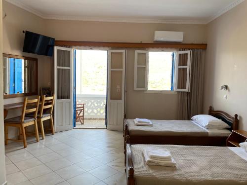 a bedroom with two beds and a table and a balcony at Hotel THE OLIVE TREE in Olympos