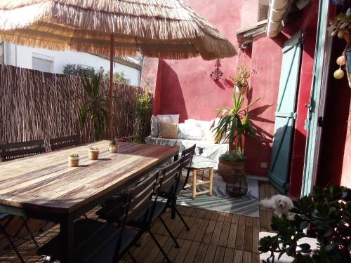una mesa de madera con sillas y una sombrilla en el patio en La maison perchee, en Aigues-Mortes
