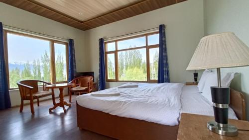 a bedroom with a bed and a table with a lamp at Niri-la Guest house Leh in Leh