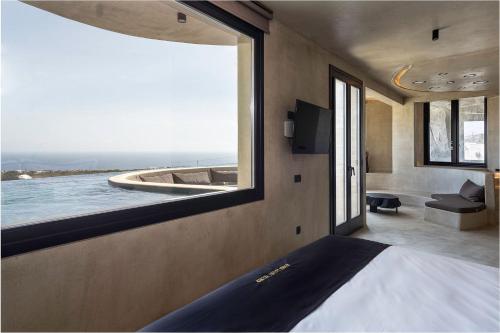 a bedroom with a view of the ocean from a window at Senses Luxury Houses in Fira