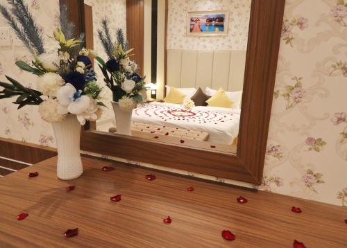 a bedroom with a mirror and flowers on a wooden floor at سما الرفاع 3 in Al Kharj