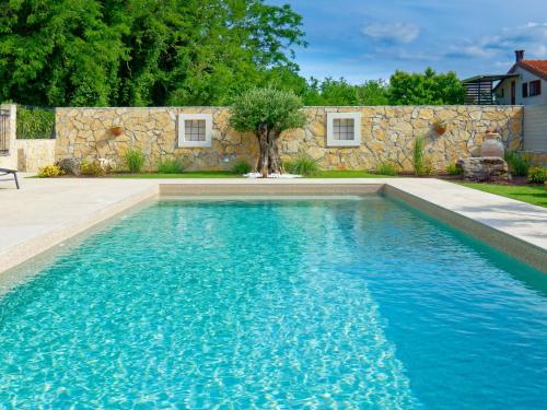 a swimming pool with blue water in front of a stone wall at Villa Morgan in Umag