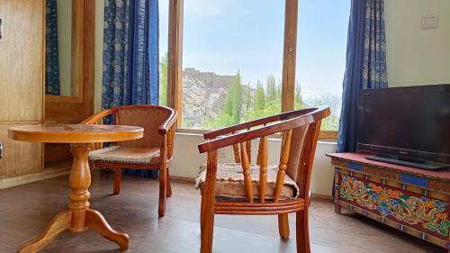 a room with a table and chairs and a television at Niri-la Guest house Leh in Leh