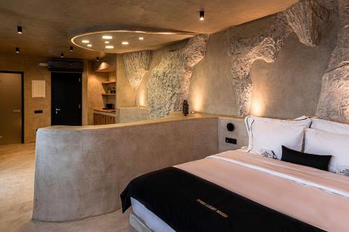 a bedroom with a large bed with a stone wall at Senses Luxury Houses in Fira