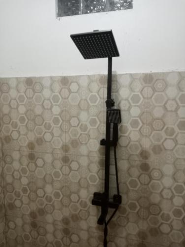 a shower head in a bathroom with a tiled wall at Homestay putih Ciwidey in Ciwidey