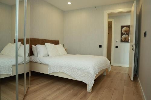 1 dormitorio con 1 cama con sábanas blancas y espejo en Prime Residence Istanbul-2-BDROOM en Estambul