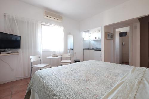 a white bedroom with a bed and a kitchen at Gil's Guest Rooms in Neve Zohar
