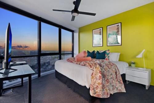 a bedroom with yellow walls and a bed and a television at Circle on Cavill - Self Contained & Privately Managed - Wow Stay in Gold Coast