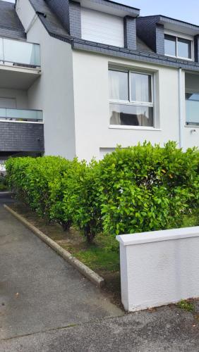 a white house with green bushes in front of it at Appartement port de Vannes in Vannes