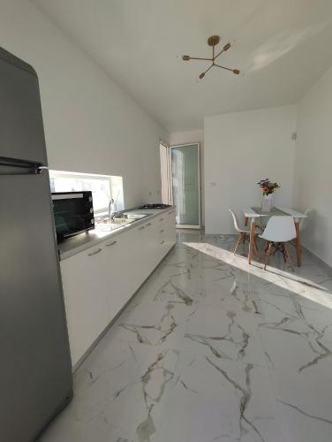 una cucina bianca con pavimenti in marmo e frigorifero di Corte I a Racale