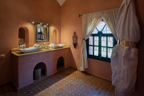 baño con lavabo, espejo y ventana en Riad Al Riadinou, en Aghmat
