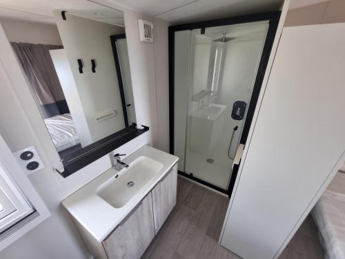 La salle de bains blanche est pourvue d'un lavabo et d'une douche. dans l'établissement Mobil Home Neuf Vue mer, à Saint-Raphaël