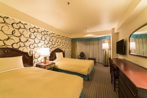 a hotel room with two beds and a flat screen tv at Rose Hotel Yokohama, The Distinctive Collection By WORLDHOTELS in Yokohama