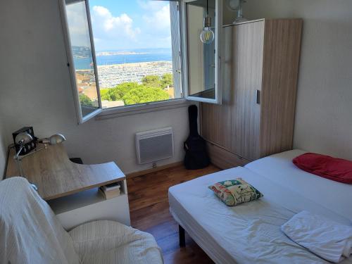 une petite pièce avec un lit et une fenêtre dans l'établissement La Pointe Rouge vue mer, à Marseille