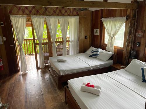 a bedroom with two beds and a balcony at White Beach Front and Cottages in Buruanga