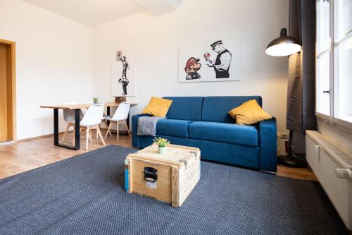 ein Wohnzimmer mit einem blauen Sofa und einem Tisch in der Unterkunft Ko-Living Space an der Oper - Street Art Design Apartments in Halle an der Saale