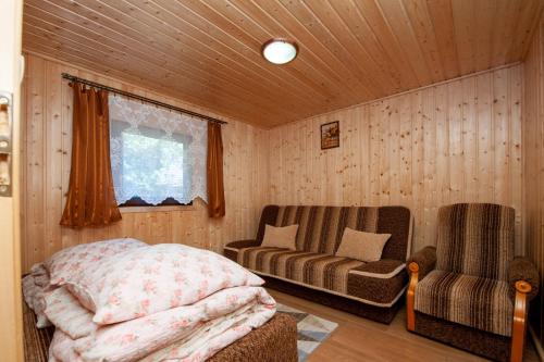 een slaapkamer met een bed, een bank en een stoel bij Domki, pokoje u Małgosi in Sztutowo