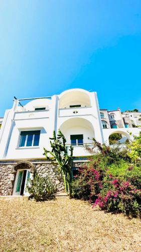 a white building with some flowers in front of it at Villa La Zagara by CapriRooms in Capri
