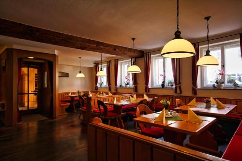 ein Restaurant mit Holztischen, Stühlen und Fenstern in der Unterkunft Hotel-Gasthof Postbräu Dingolfing in Dingolfing