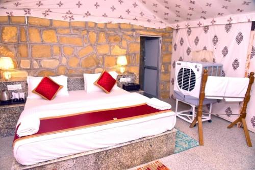 a bedroom with a bed and a stone wall at The Jaisalmer Heritage Safari Camp in Sām
